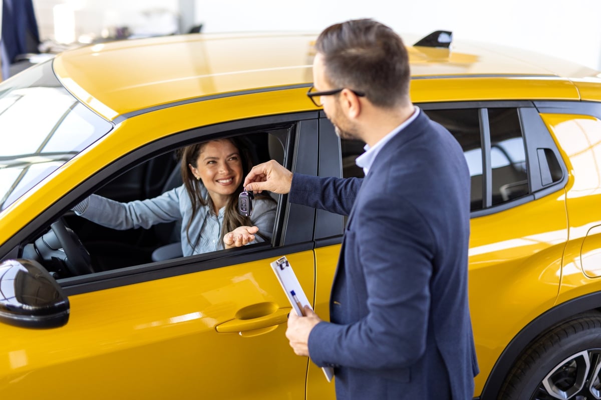 Young woman driver receiving car keys from a rental manager